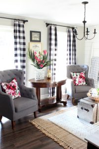 Neutral living room with buffalo plaid curtains and red floral accents.